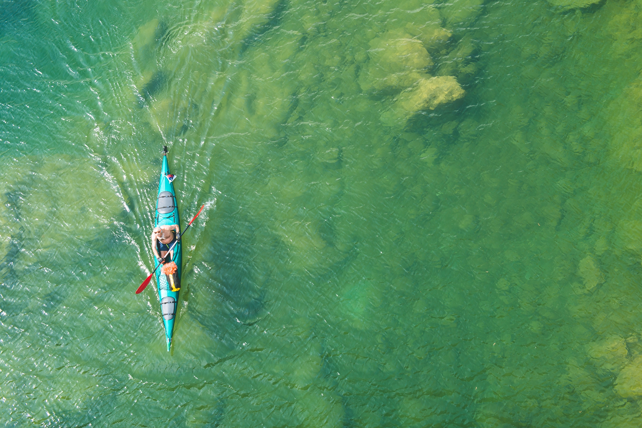 Senior with white hair, braided beard, moustaches,  shirtless, is kayaking in the Soca River beautiful waters, Slovenia, Europe. High angle view. Nikon D3x.