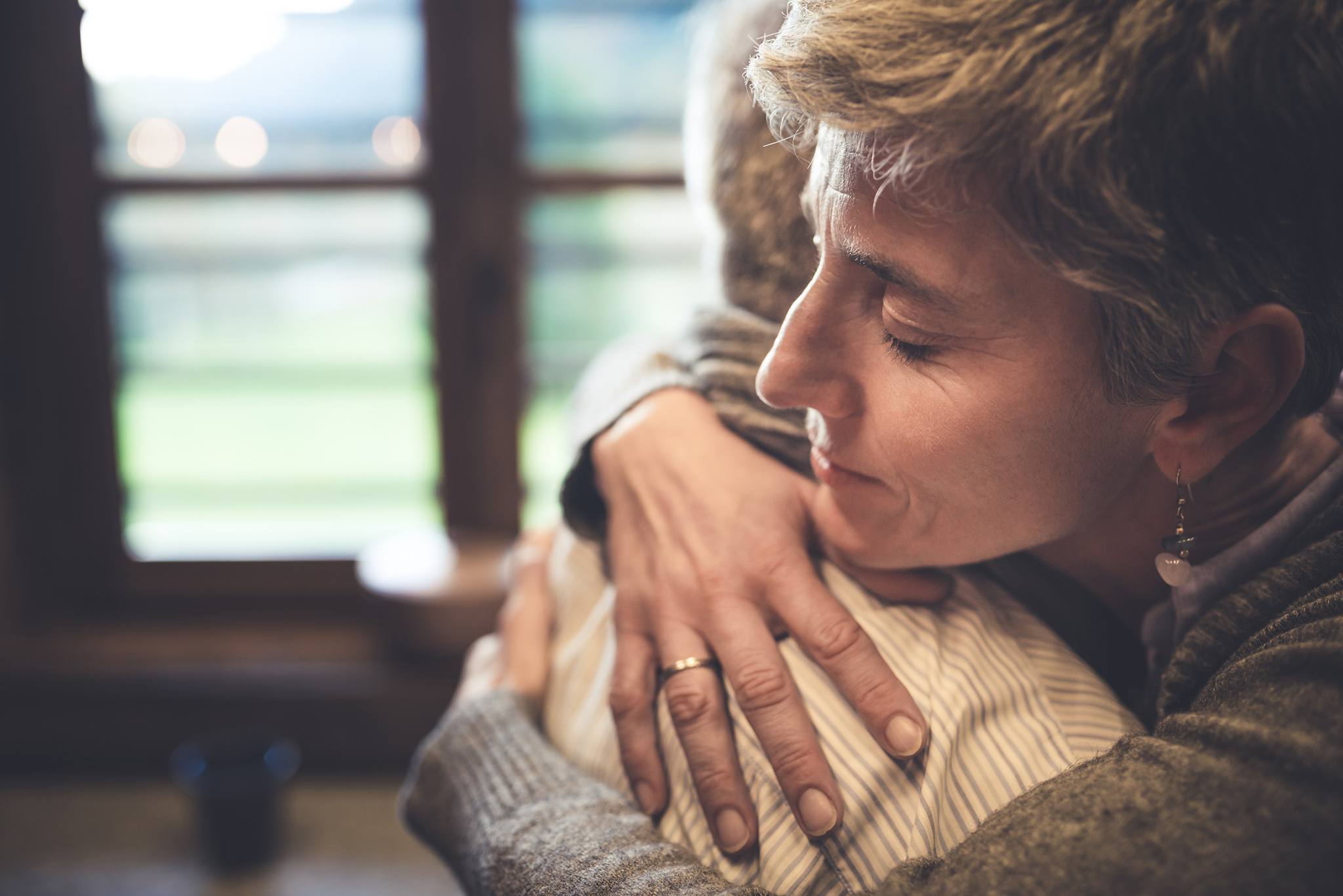 Senior couple embrace themselves in their kitchen