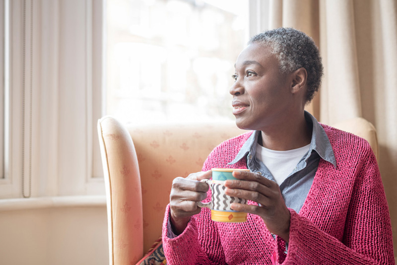 Pensive woman in her 50s with short grey hair looking out of window