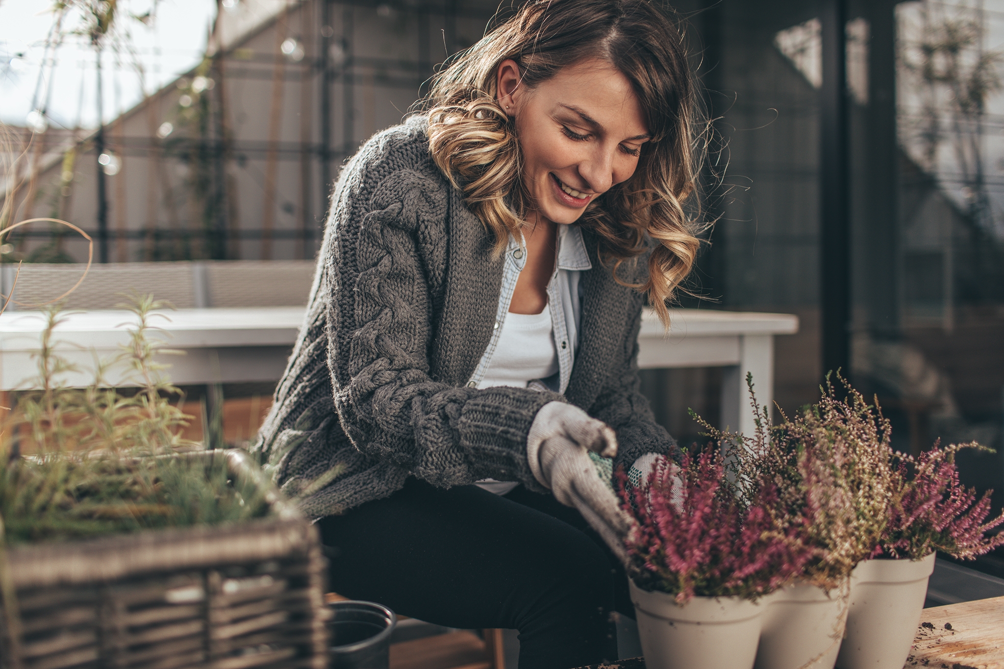 Photo of a young woman taking care of her rooftop garden on the balcony over the city, on a beautiful autumn day